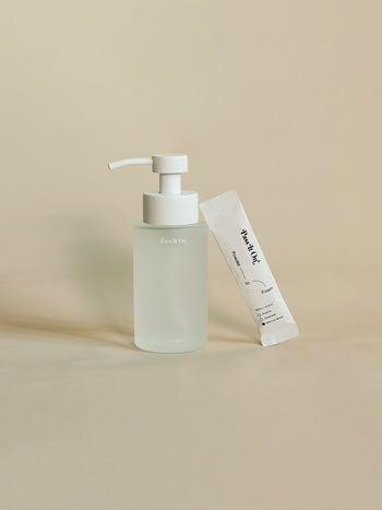 The Pass It On 0.02 Refillable Hand Wash Set in Marine Moss features a frosted glass pump bottle with a white dispenser and a matching sachet, both with minimalistic, modern packaging and subtle branding from Pass It On.