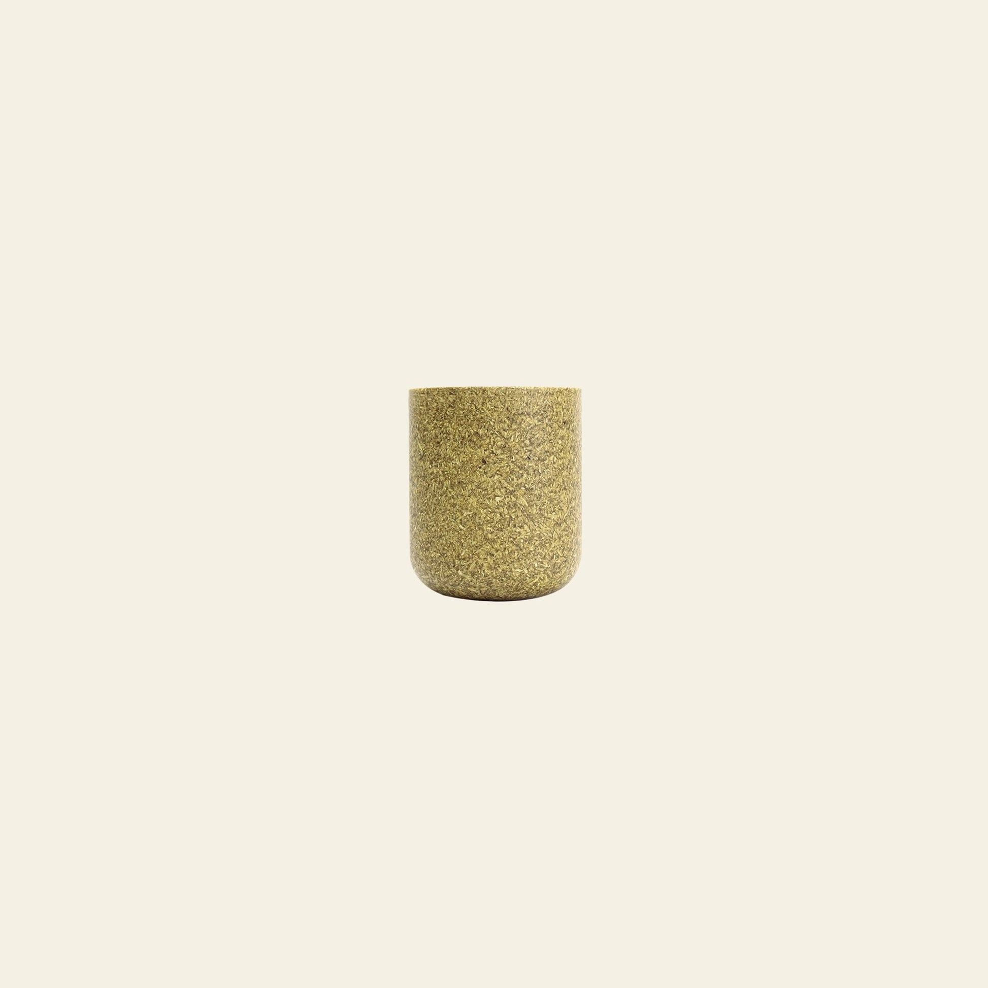 The Pass It On Capsule Cup, Rice Husk by Pass It On—a small cylindrical cup made from upcycled rice husks in mottled gold—sits centered on a plain beige background, offering an eco-conscious choice for your daily routine.