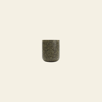 The Pass It On Capsule Cup, Rice Husk—a small, cylindrical cup made from upcycled rice husks with dark speckles—is centered on a plain, light beige background.