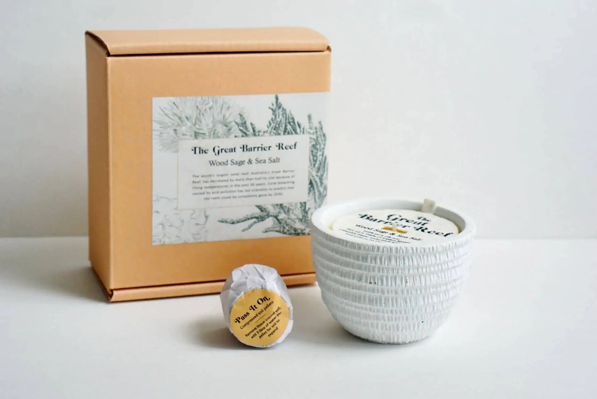 The Pass It On Great Barrier Reef Candle gift set includes a peach box, a white textured candle with lid, and a round soap in white paper with yellow label, all infused with an invigorating mineral salt scent.