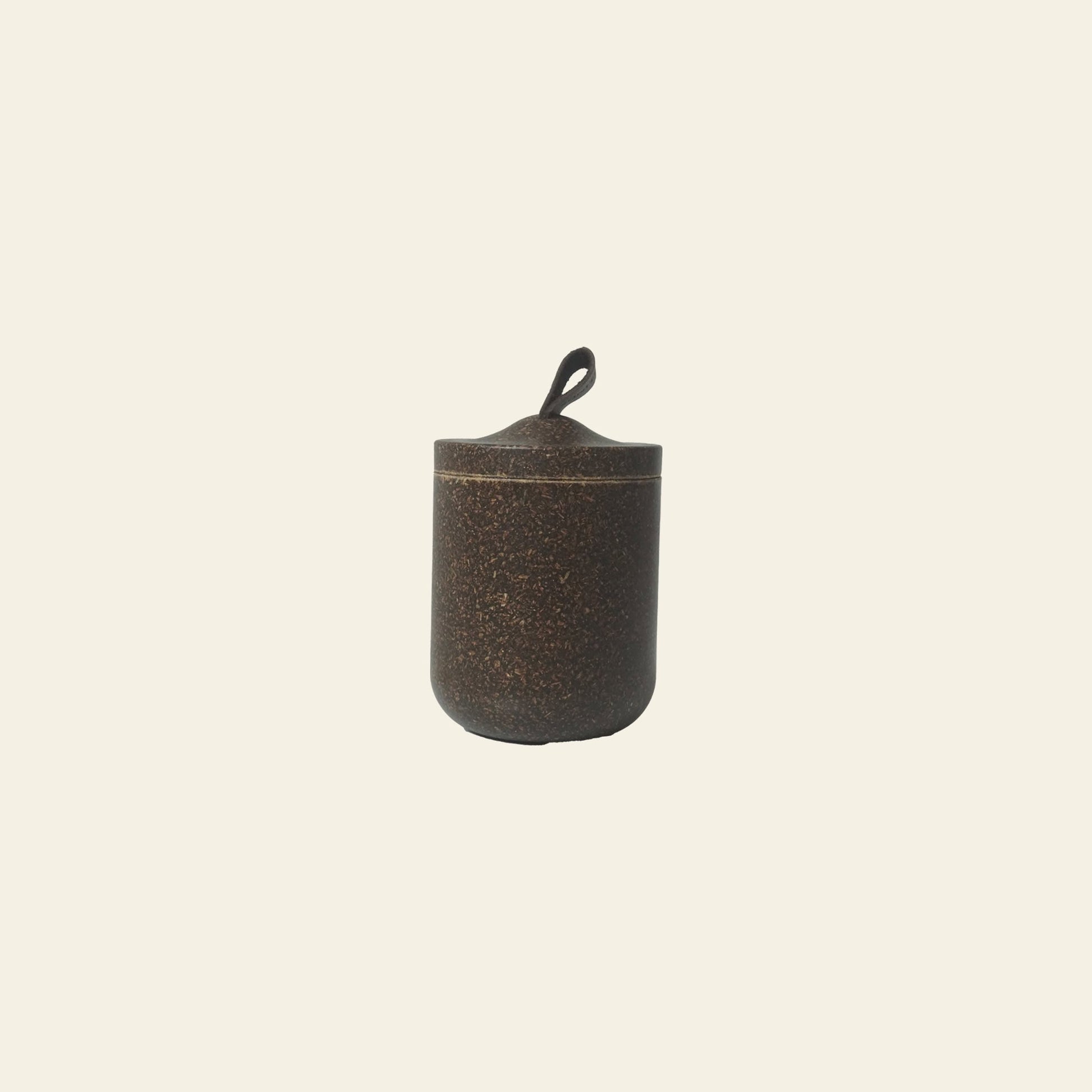 The Pass It On Tagine Tall Box, Rice Husk, by Pass It On, is a small, cylindrical dark brown box with a loop-handled lid—crafted from upcycled rice husks and perfect for eco-conscious living.