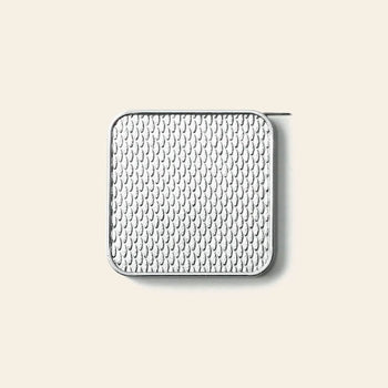 A square, silver-edged object with a white, textured surface and a small, thin pin extending from its upper right corner rests against a plain beige background. The Penco Pocket Measure by Penco is a compact stainless steel measuring tape featuring a retro-inspired design that blends functionality with vintage charm.