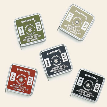 Five Penco Pocket Measure tape measures in green, khaki, orange, black, and navy are arranged on a light beige background. Each vintage-inspired measuring tape by Penco features "2M" and "No. 16" markings with a metal tape partially extended, highlighting their retro design.