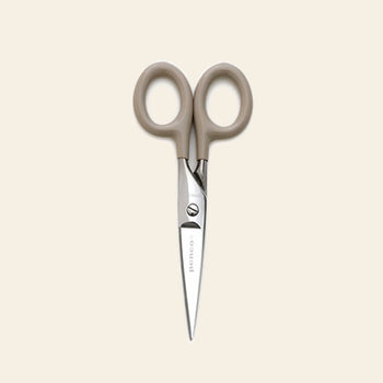 The Penco Stainless Steel Scissors S by Penco, featuring compact stainless steel blades and beige handles, is displayed vertically with the blades pointing downward against a light cream background.