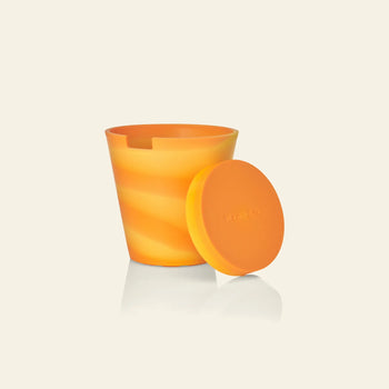 A Plastic Ark Dirty Pot snack cup in orange swirled silicone, with a matching lid showing the Plastic Ark logo, is displayed on a plain background—a smart eco-friendly option for families seeking alternatives to recycled plastic pots.