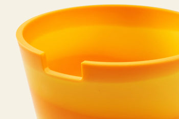 Close-up of the Plastic Ark Dirty Pot by Plastic Ark, a bright yellow sustainable plant pot with a notched rim, set against a plain light background.