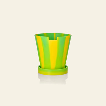 The Plastic Ark Dirty Pot by Plastic Ark is a small, striped sustainable plant pot with a matching saucer, featuring bright yellow and green vertical bands, shown against a plain, light beige background.
