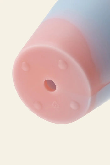 Close-up of the Plastic Ark Dirty Pot by Plastic Ark, a sustainable pastel-colored plant pot with a pink base, central hole, four small raised bumps, and a light blue edge. Made from recycled plastic.