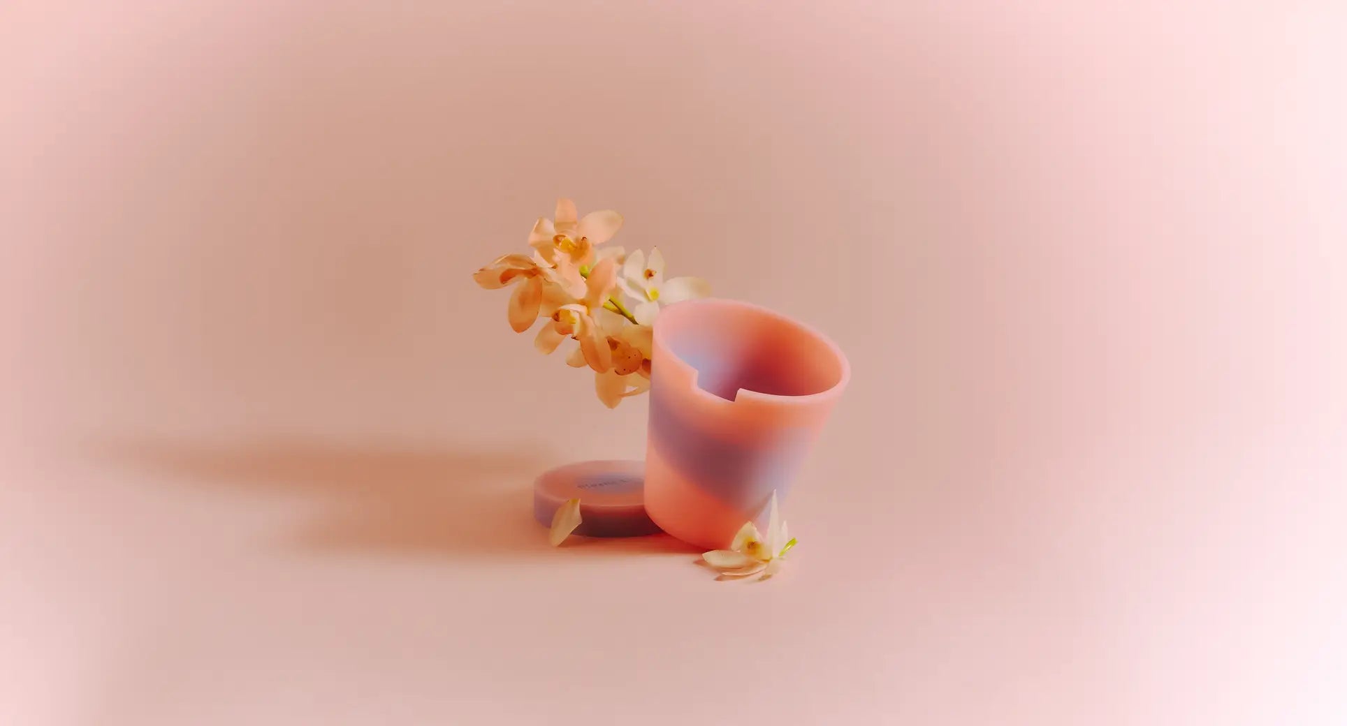 The Plastic Ark Dirty Pot by Plastic Ark, featuring a pastel pink and purple marbled design, is tilted on its side with delicate white flowers inside and around it, set against a soft light pink background.