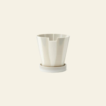 The Plastic Ark Dirty Pot by Plastic Ark is a modern white cylindrical recycled plastic pot with vertical grooves and a matching round base, shown against a plain cream background.