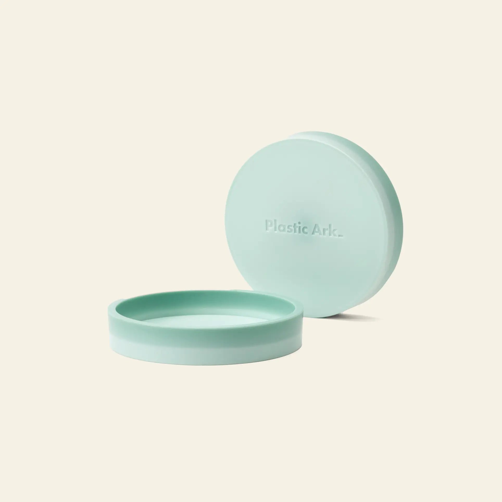 The Plastic Ark Dirty Pot, a round, light green recycled plastic pot with a matching embossed lid, sits on a cream background—an eco-friendly planter by Plastic Ark, perfect for modern spaces.
