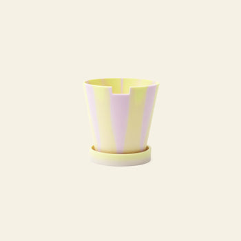 The Plastic Ark Dirty Pot by Plastic Ark is a small plant pot made from recycled plastic, featuring vertical pastel yellow and light purple stripes, with a matching round saucer against a plain beige background.