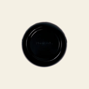 A black, round Plastic Ark Fat Bowl from Plastic Ark is seen from above on an off-white background. Plastic Ark is faintly visible at the center, highlighting its recycled plastic construction and customizable design.