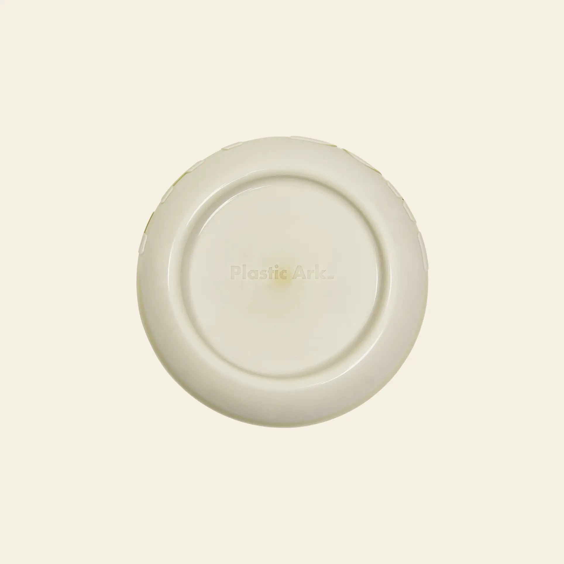A plain off-white Plastic Ark Fat Bowl flying disc made from recycled plastic, featuring the Plastic Ark logo faintly visible at the center, set against a light beige background.