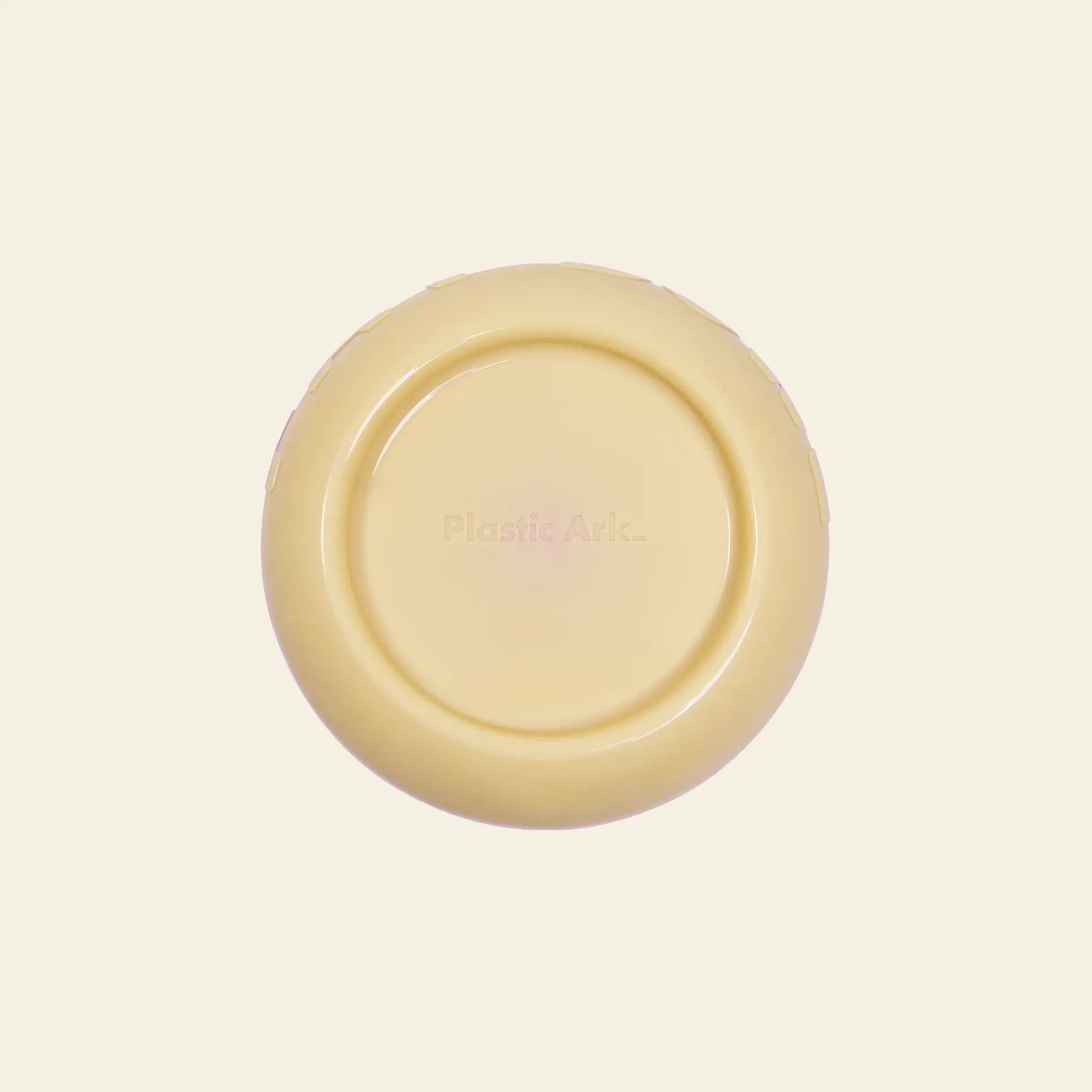 The Plastic Ark Fat Bowl by Plastic Ark is a round, beige bowl made from recycled plastic, featuring the brand name at its center. Its modular design makes it ideal for pets and its shown on an off-white background.