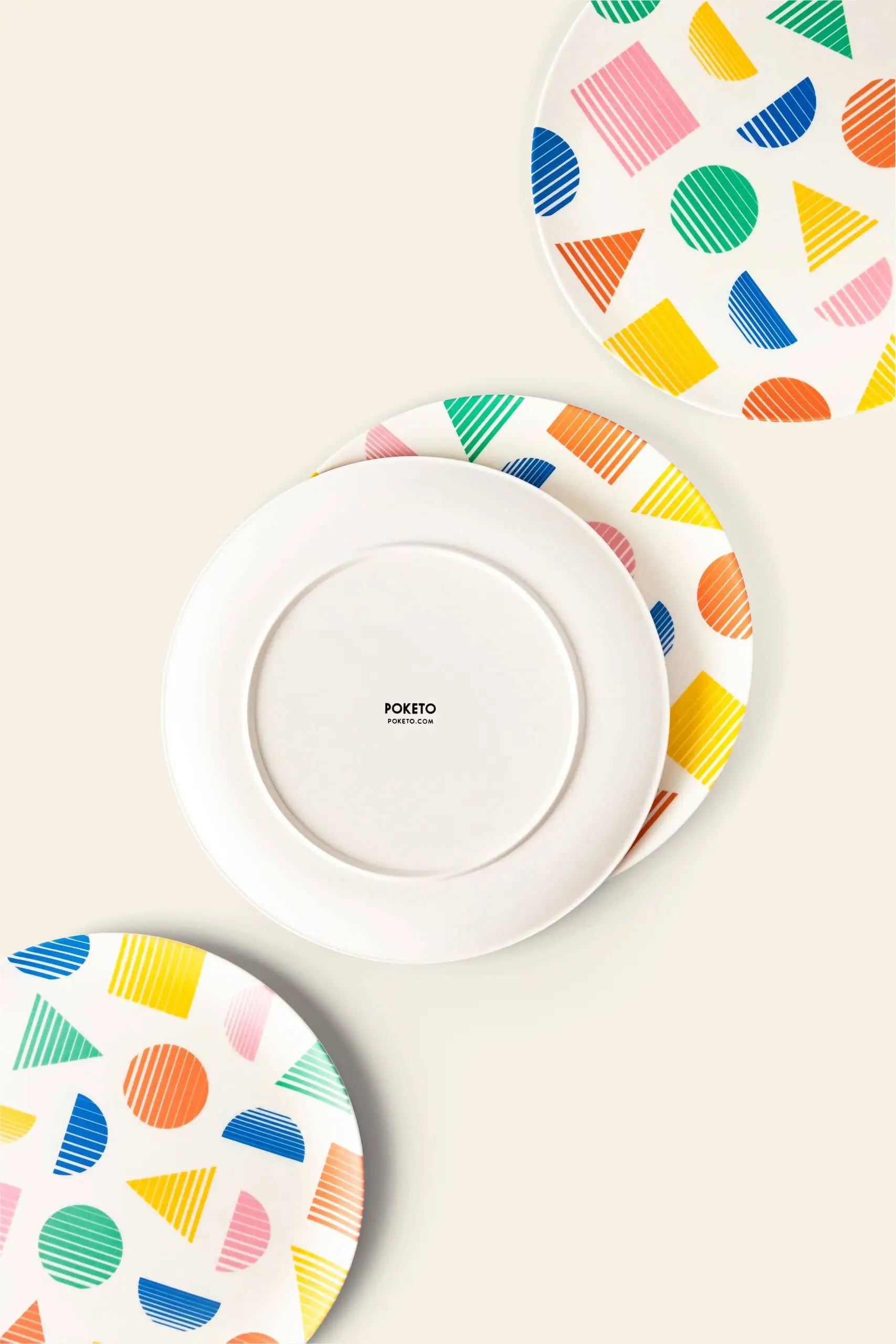 Set of four Poketo Bamboo Dinner Plates featuring vibrant geometric patterns in blue, yellow, pink, orange, and green; one plate is flipped to display a plain white back with the Poketo logo—ideal for eco-friendly gatherings.