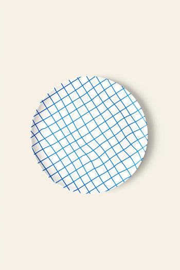 The Poketo Bamboo Dinner Plate by Poketo features a round white design with a blue crisscross grid, shown on a beige background—ideal for eco-friendly dinner parties.