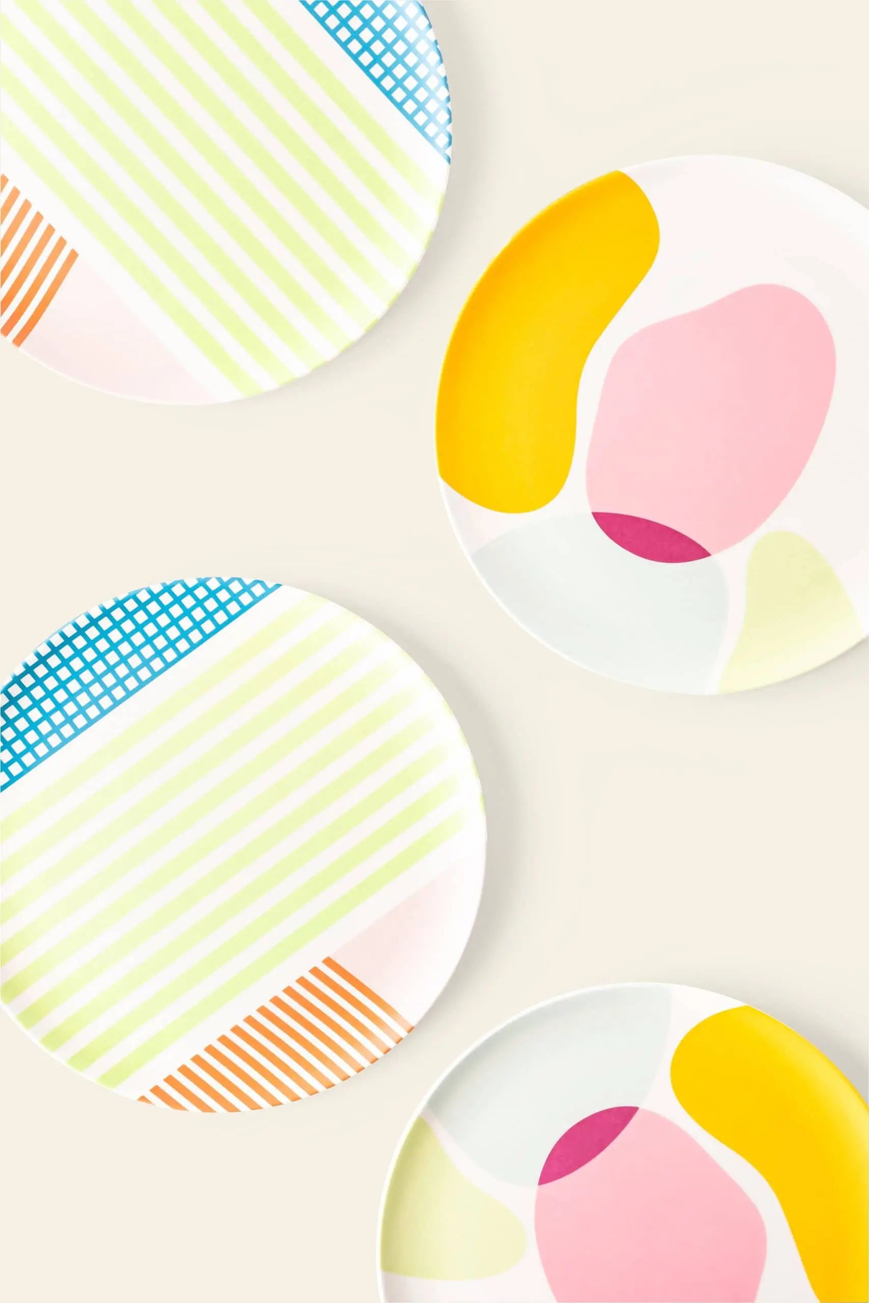 The Poketo Bamboo Salad Plate set includes four eco-friendly plates with colorful abstract designs in pink, yellow, blue, orange, and green—perfect for a sustainable dining setup. Brand: Poketo.