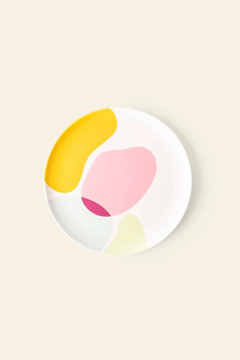 The Poketo Bamboo Salad Plate by Poketo is an eco-friendly, white plate with abstract shapes in yellow, pink, dark pink, and light green on beige—ideal for sustainable dining.