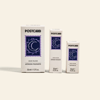 Three white rectangular Postcard boxes, each labeled Postcard Anywhere Fragrance, 10ml - Moon Bloom, showcase a purple crescent moon and star design and offer the brand’s captivating scent notes.