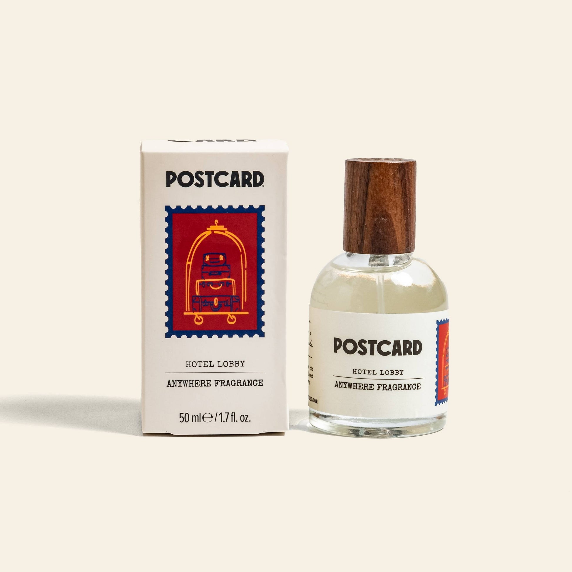 A 50ml bottle of Postcard Anywhere Fragrance – Hotel Lobby by Postcard sits beside its box, which displays an illustrated red luggage cart on a blue background.