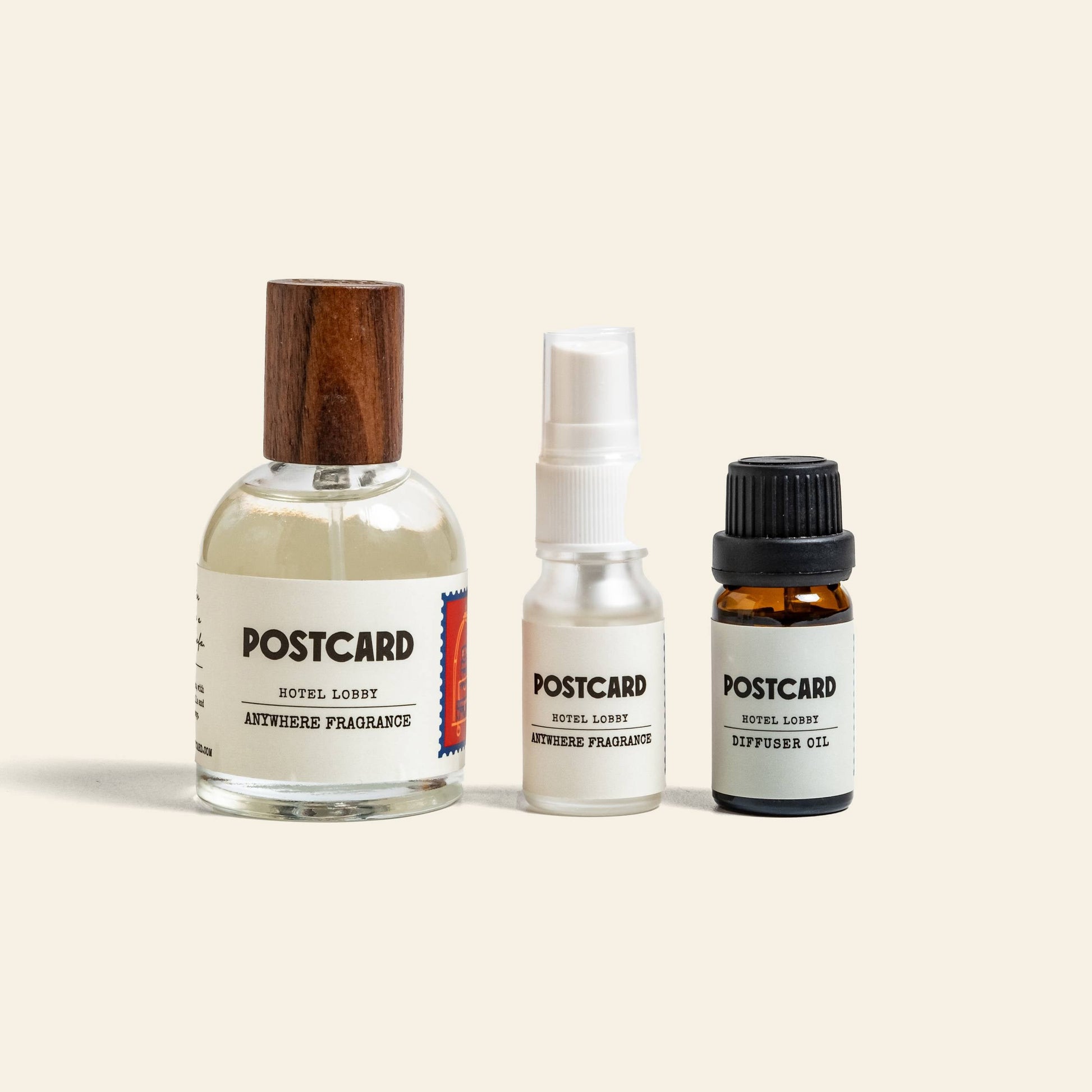 Three bottles of Postcard Anywhere Fragrance, 50ml—Hotel Lobby, from Postcard, including a wooden cap spray, white spray, and amber dropper bottle—evoke versatile Hotel Luxury on a light background.