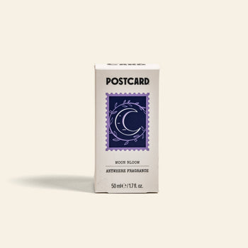 A white Postcard box labeled Postcard Anywhere Fragrance, 50ml - Moon Bloom features a purple crescent moon and leaves stamp design, highlighting the Moon Bloom scent notes.