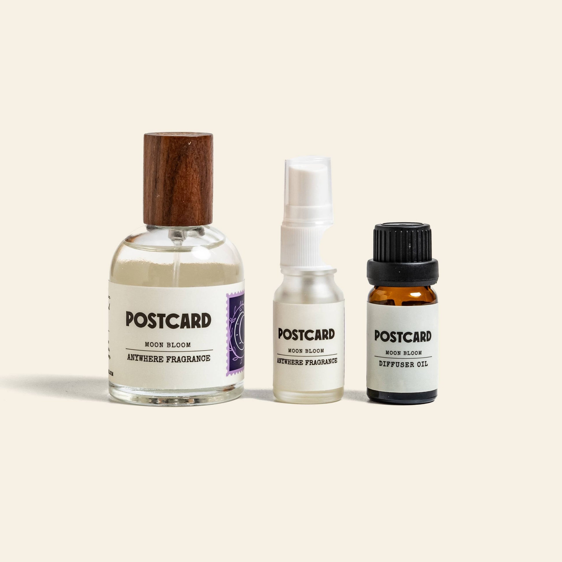 Three Postcard glass bottles in different sizes feature calming Moon Bloom scents; two are Anywhere Fragrance sprays, while the third—Postcard Diffuser Oil, 10g with a black cap—is ideal for your lunar lounge.