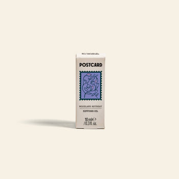 Postcard Diffuser Oil, 10g - Woodland Retreat, comes in a small box featuring a blue stamp with leaves and a house on beige—inviting calming forest-inspired scents for serene relaxation.