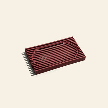 The Postcard Lattice Soap Dish by Postcard features a rectangular, dark red design with raised horizontal ridges on beige resin, making it recyclable and ideal for minimalist or zero-waste lifestyles.