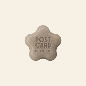The Postcard Shampoo Bar, 60g - Coffee Spot by Postcard is a beige, star-shaped bar embossed with POST CARD SHAMPOO. Made with upcycled coffee grounds, it helps refresh oily scalps and is shown against a plain light background.