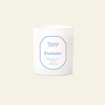 The Reminds Me Of Poolside Candle, 10oz by Reminds Me Of, featuring notes of coconut milk, coconut lotion, amyris, and tonka bean in a white glass jar, is displayed on a beige background.