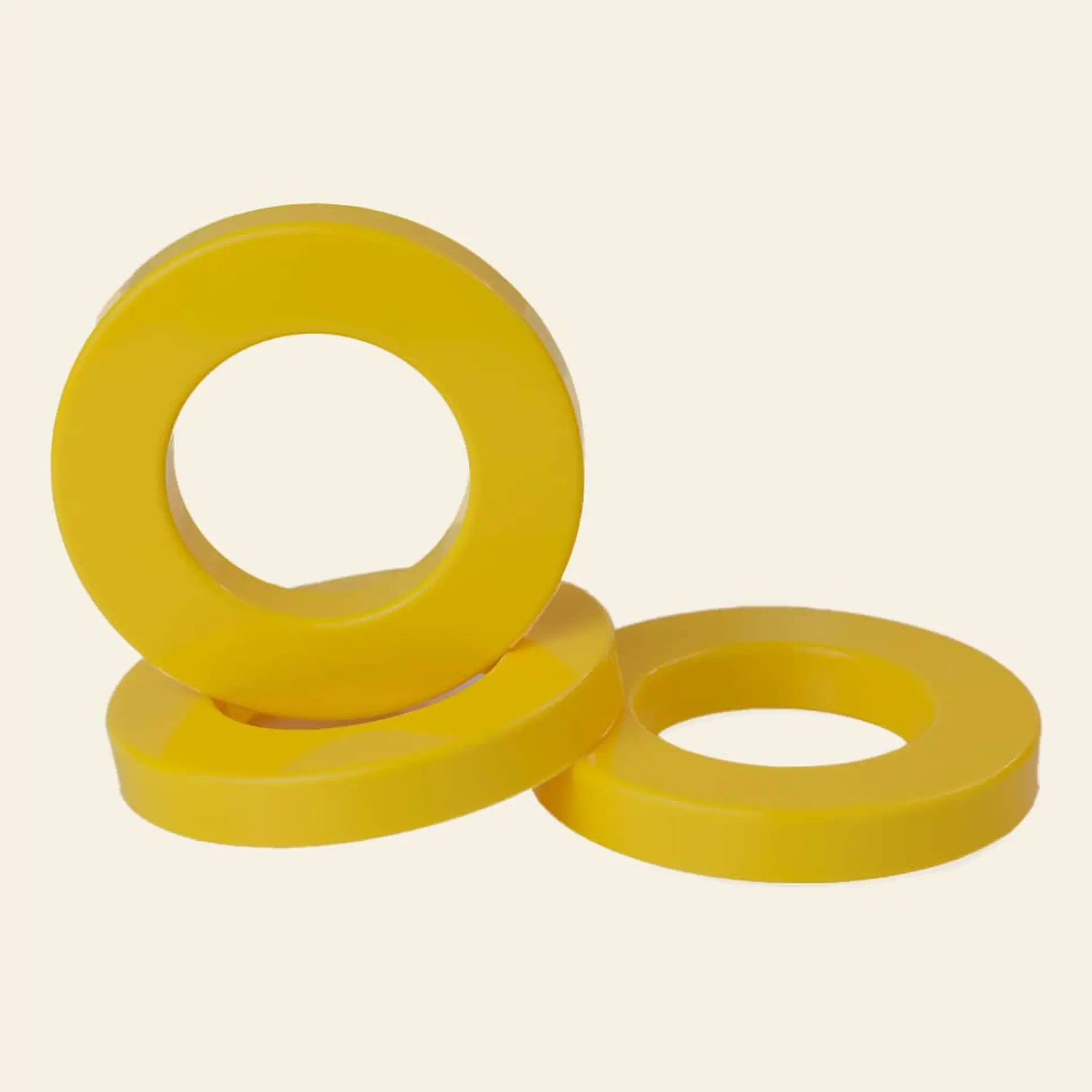 Three vibrant Ring A Date Calendar Rings by Ring-A-Date are arranged on a light beige background—one upright, two lying flat and overlapping, each featuring a large central hole.