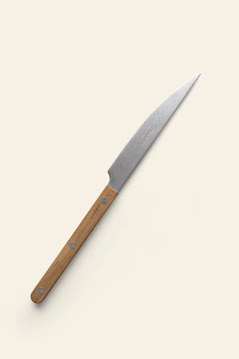 The Sabre Bistrot Vintage Dinner Knife by Sabre features a pointed stainless steel blade and a light brown wooden handle with three metal rivets, displayed on a light beige background and channeling classic French bistrot style.