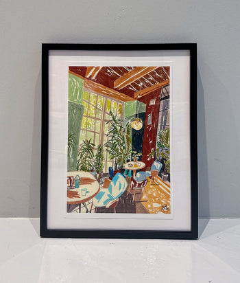 Autumn Triplets N.1 (Limited Edition Run) by Sarah Mari Shaboyan is a vibrant framed print of a cozy sunlit space with plants, tables, and chairs in autumn tones. Includes Certificate of Authenticity.