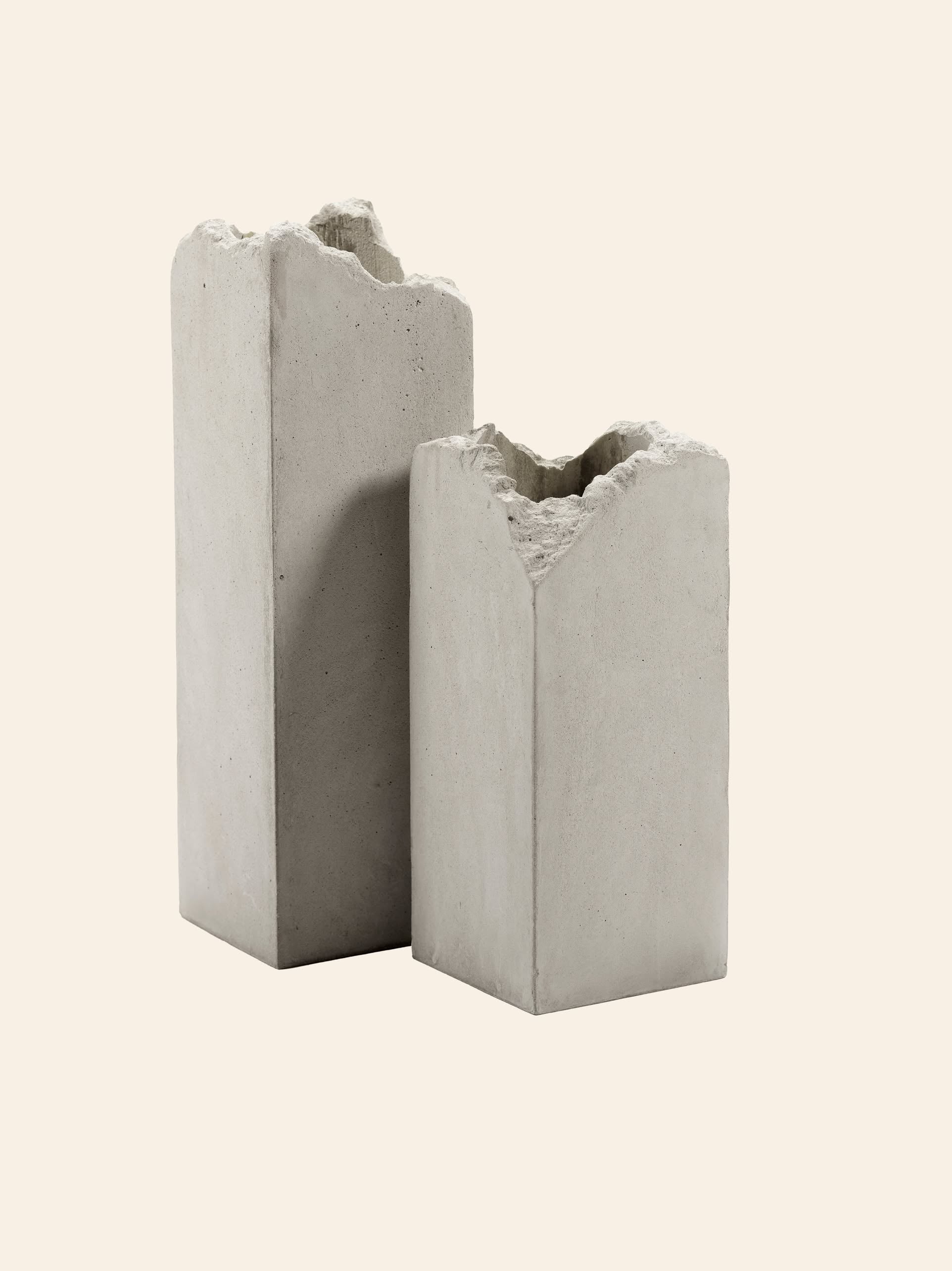 Two rectangular, gray Serax Broquaine Concrete Vase S pieces stand side by side on a light beige background—modern artistry from Serax with textured tops and minimalist appeal.