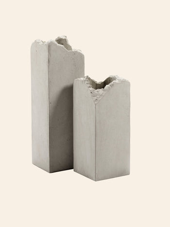 Two rectangular, gray Serax Broquaine Concrete Vase S pieces stand side by side on a light beige background—modern artistry from Serax with textured tops and minimalist appeal.