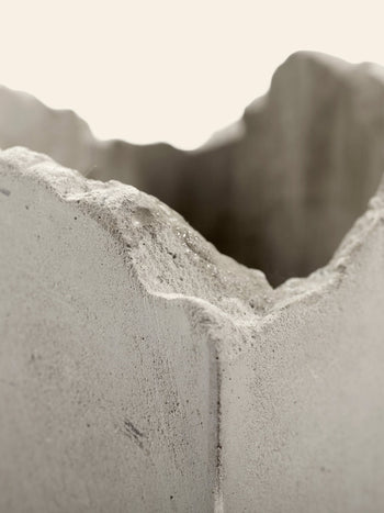 Close-up of the rough, jagged edge of the Serax Broquaine Concrete Vase S in grey by Serax, featuring an irregular wavy surface texture with an out-of-focus background, reminiscent of Patrick Pariss modern artistry.