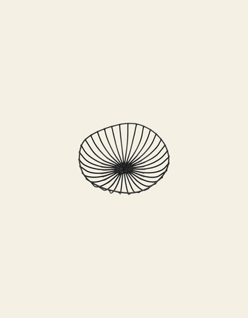 A simple black line drawing of the Serax Catu Bread Basket L by Serax, a shallow round metal basket with an open radiating pattern in Antonino Sciortinos style, centered on a light beige background.