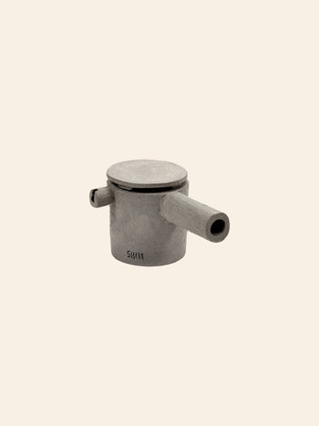 The Serax Fck Teapot N°3 - Grey Brown by Serax is a minimalist teapot with a cylindrical shape, flat lid, short spout, and side handle in a concrete-like finish, shown against a plain beige background.