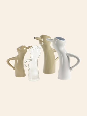 Four pitchers are displayed together, including the Serax Monsieur Cruchot Jug L in taupe with sculptural curves and a clear glass pitcher, all set against a plain light background—ideal for versatile home decor.