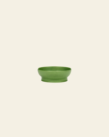The Serax Ra Bowl S - Green by Serax is a small, round green porcelain bowl with a slightly flared base, shown against an off-white background—an elegant tableware piece for any setting.