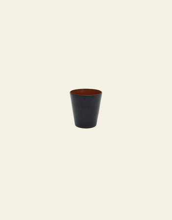 A small, plain, black conical cup with a wide opening and tapered sides from the Serax Terres De Rêves collection is centered on a light beige background.