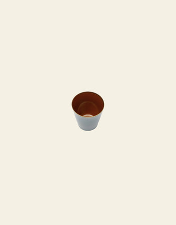 The Serax Terres De Rêves Conical Cup M, featuring a brown handcrafted glaze inside and a light gray exterior, is centered on a plain light beige background.