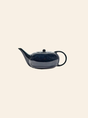 The Serax Terres De Rêves Teapot in dark blue, featuring a curved spout, round handle, and matching lid, sits elegantly against a light beige background—an ideal addition to your refined tableware collection.