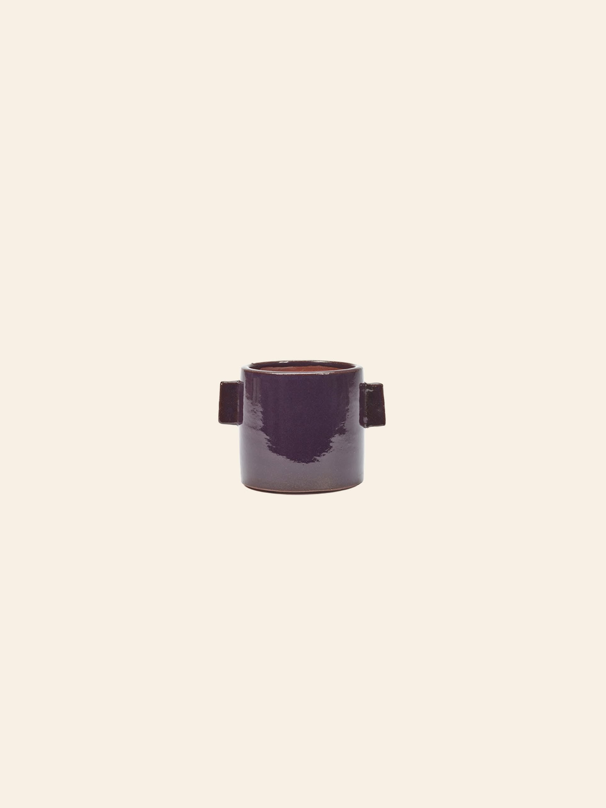 The Serax Urban Jungle Glazed Flower Pot M in glossy dark purple aubergine ceramic features two rectangular handles and is set against a plain beige background.