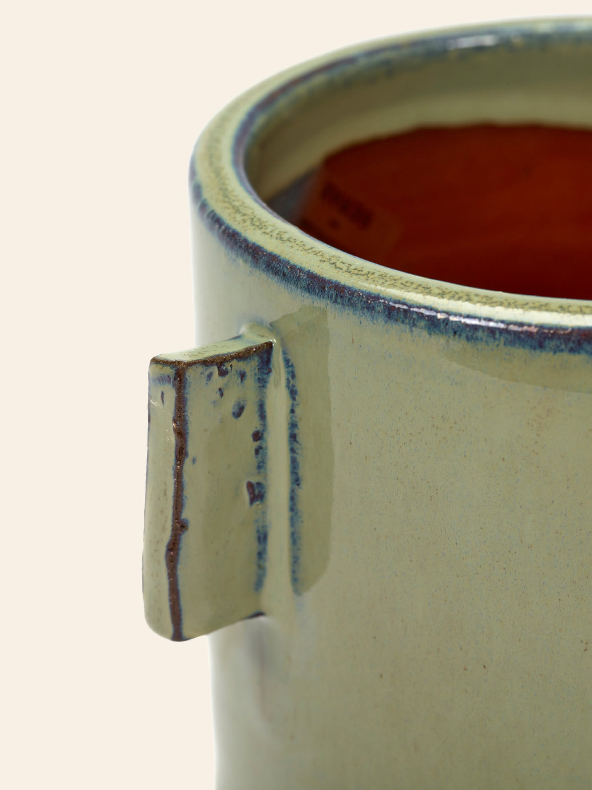 The Serax Urban Jungle Glazed Flower Pot S in grey features a pale green, slightly textured finish, square handle, rounded rim with blue detailing, and reddish-brown interior—perfect for adding elegance to any indoor space.