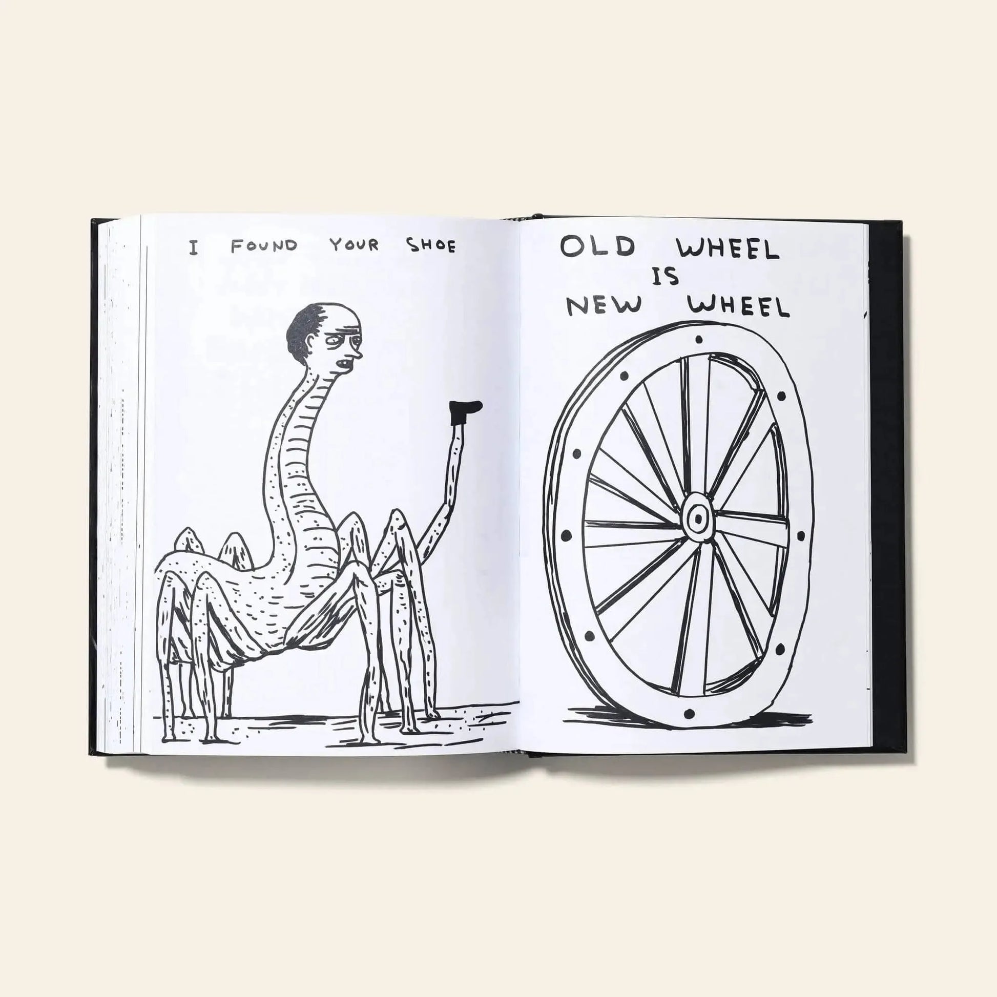 An open Shrig Shop David Shrigley - I Am The Jug You Are The Glass book by Shrig Shop displays a surreal human-headed spider with a shoe on one page, and a wagon wheel illustration with the text “OLD WHEEL IS NEW WHEEL” on the other.