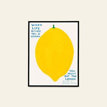 The Shrig Shop David Shrigley - When Life Gives You A Lemon (60x80) is a framed artwork featuring a big yellow lemon with blue text: “WHEN LIFE GIVES YOU A LEMON YOU MUST EAT THE LEMON ALL OF IT INCLUDING THE SKIN” on white.