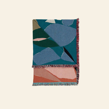 The Slowdown Studio Barbosa Throw features abstract geometric patterns in blue, green, and gray on top, peach, pink, and terracotta underneath, and has multicolored fringed edges. Crafted from recycled cotton by Slowdown Studio.